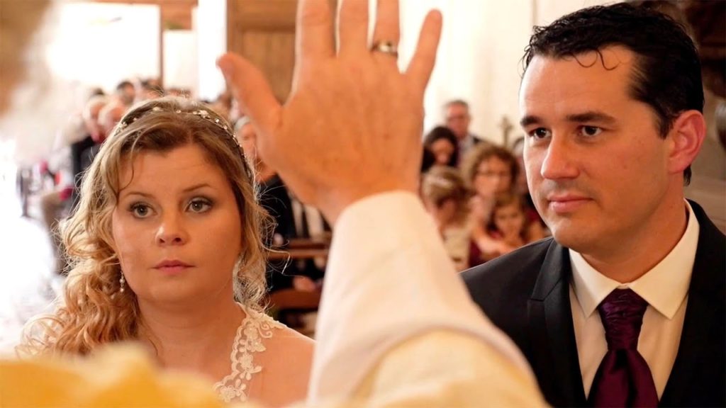 Épouse et époux qui reçoivent la bénédiction d'un prêtre dans une église pour leur mariage