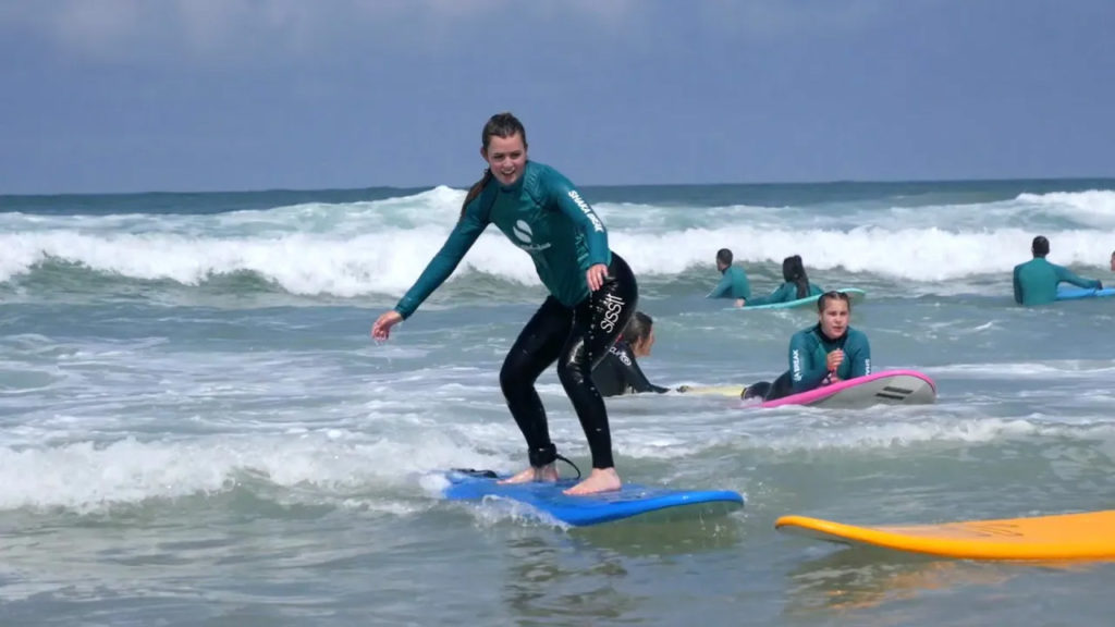 Fille surfeuse qui fait du surf sur une vague de l'océan atlantique à la plage de Vieux-Boucau dans les Landes
