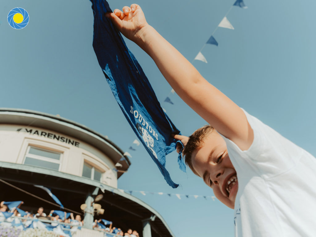 Enfant sur les épaules de son père brandissant un foulard bleu aux Fêtes de Soustons dans les Landes