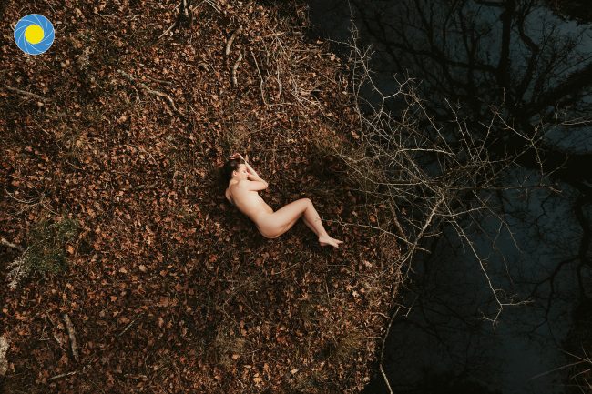 Une femme allongée sur des feuilles dans une forêt landaise à l'automne